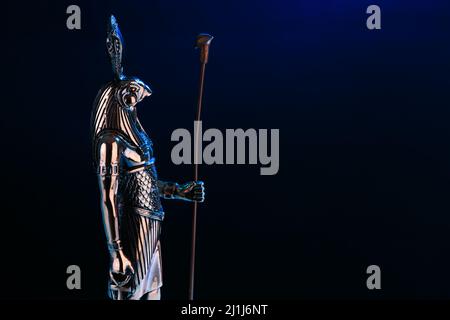 Statue en métal du dieu Egyptien Ra avec la tête d'un faucon sur fond noir avec illumination bleue. Photo de haute qualité Banque D'Images