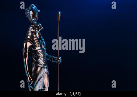 Statue en métal du dieu Egyptien Ra avec la tête d'un faucon sur fond noir avec illumination bleue. Photo de haute qualité Banque D'Images