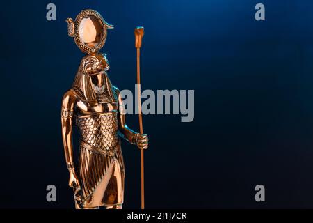 Statue en métal du dieu Egyptien Ra avec la tête d'un faucon sur fond noir avec illumination bleue. Photo de haute qualité Banque D'Images