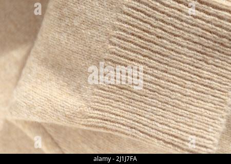 Détails d'un pull en laine tricoté, fond texturé. Pull en tricot cachemire replié, coloris beige. Tricots élégants Banque D'Images