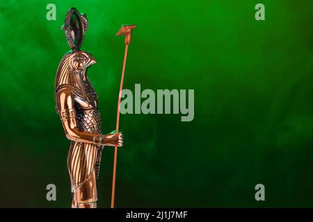 Statue d'or du dieu Egyptien Ra avec la tête d'un faucon sur fond noir avec illumination verte. Photo de haute qualité Banque D'Images