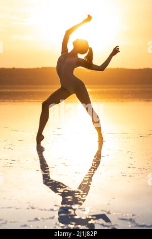 La danseuse de ballet pose dans le lagon face au soleil qui brille le ciel Banque D'Images