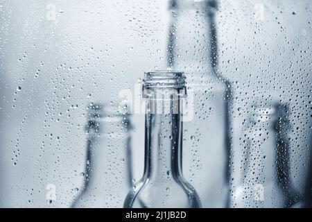 Bouteilles transparentes en verre dans des gouttes d'eau. Plats en verre. Banque D'Images