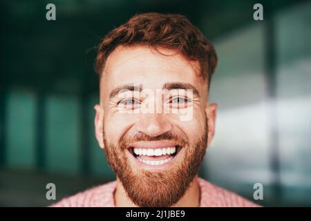 Jeune homme heureux souriant sur l'appareil photo extérieur - Focus sur le visage Banque D'Images