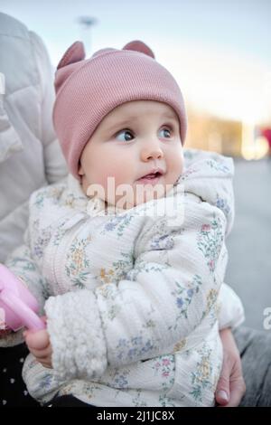 Maman tient le bébé et joue avec lui dans la rue. Bébé de six mois dans un chapeau Banque D'Images