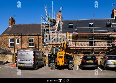 Modernisation, rénovation d'une rangée de maisons (toit sur échelle, homme en cabine de chauffeur jaune JCB, échafaudage) - Knaresborough, North Yorkshire, Angleterre, Royaume-Uni. Banque D'Images