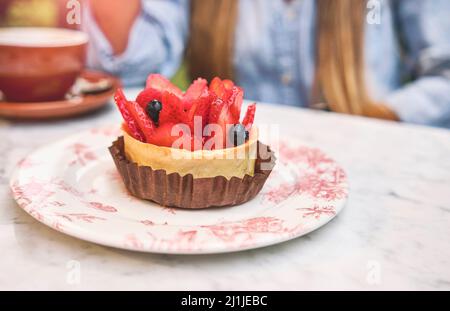 Jeune femme qui goûte un gâteau à la fraise, foyer sélectif. Banque D'Images