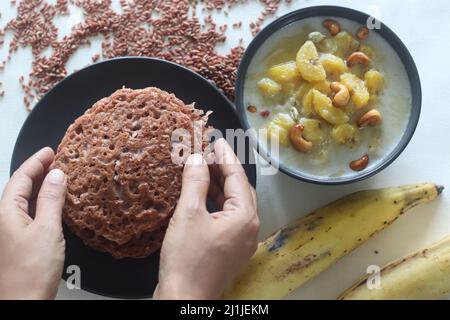 Crêpes de riz rouge. Crêpes faites d'une pâte fermentée de riz rouge et de noix de coco. Également appelé riz rouge aPAM dans le Kerala. Servi avec un ragoût de plantain mûr. Banque D'Images