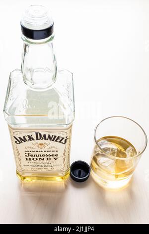 Moscou, Russie - 26 mars 2022 : verre et bouteille ouverte de liqueur au miel du Tennessee Jack Daniel sur table pâle. C'est de la liqueur de miel mélangée avec moins de t Banque D'Images