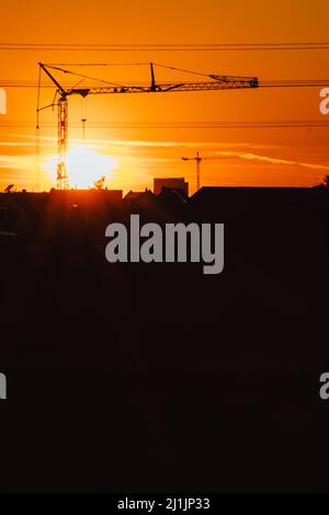 Silhouette de grue de construction haute dans le ciel orange coucher de soleil montre le chantier de construction avec l'ingénierie pour les bâtiments modernes et les architectes de développement de ville Banque D'Images