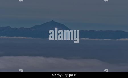 Vue lointaine de l'île de Ténérife avec le Mont Teide (3 715 m) au-dessus d'une mer de nuages vus du Parc naturel de Tamadaba dans les montagnes de Grand Canaria. Banque D'Images