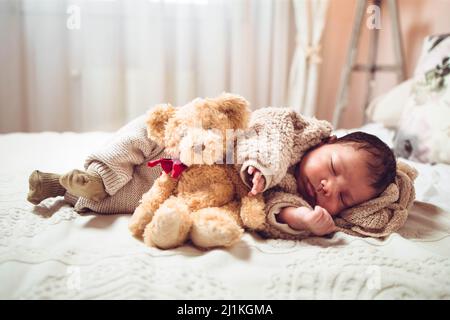 Bébé multiethnique bébé garçon dormant sur un lit. Aspect confortable avec ours en peluche Banque D'Images