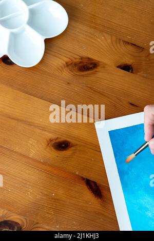 Une image plate de style de pose d'accessoires d'art sur un fond de style en bois avec une main faisant une peinture Banque D'Images