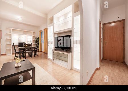 Entrée à un salon avec une table à manger en bois sombre et des chaises assorties avec des accents jaunes pour assortir les rideaux dans un appartement de location de vacances Banque D'Images