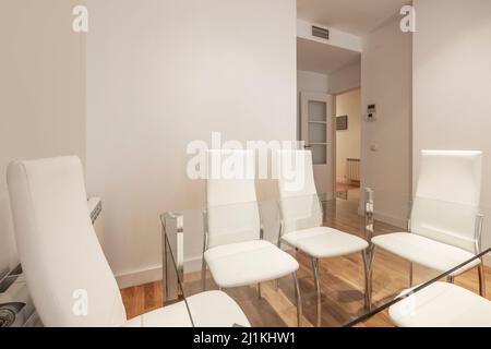 Salle de séjour avec table à manger en verre, chaises rembourrées blanches, portes en bois et en verre blanc et parquet en chêne français Banque D'Images