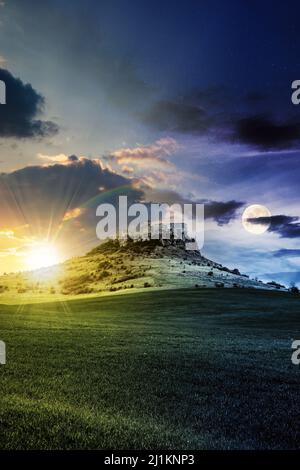 concept de changement d'heure de jour et de nuit au-dessus du château sur la colline. paysage de fantaisie composite. prairie herbeuse au premier plan. sommets rocheuses de la crête Banque D'Images