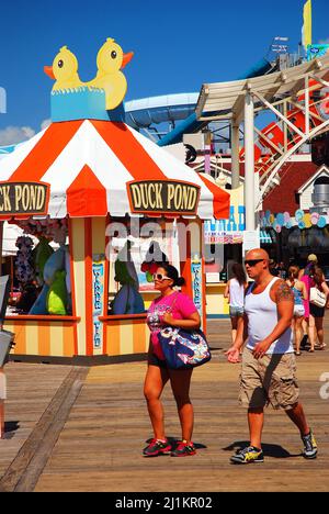 Un couple marche parmi les manèges et les jeux de carnaval sur la promenade à Wildwood, New Jersey Banque D'Images