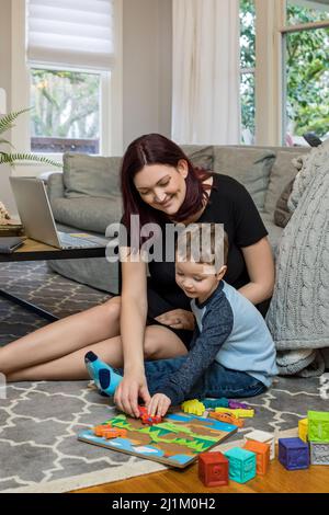 Une belle maman enceinte essayant de travailler à la maison avec un tout-petit Banque D'Images