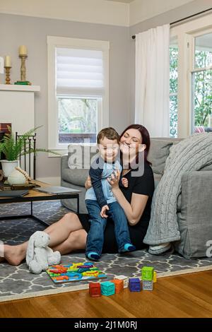 Une belle maman enceinte essayant de travailler à la maison avec un tout-petit Banque D'Images