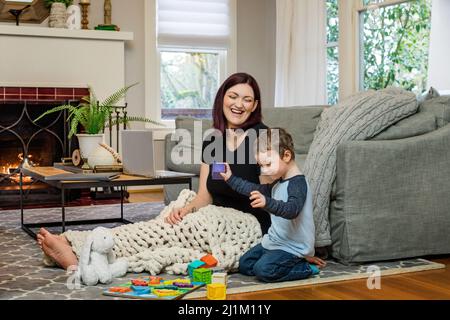 Une belle maman enceinte essayant de travailler à la maison avec un tout-petit Banque D'Images