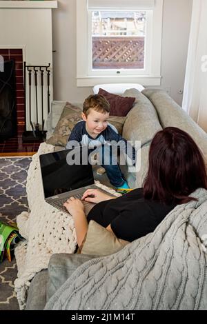 Une belle maman enceinte essayant de travailler à la maison avec un tout-petit Banque D'Images