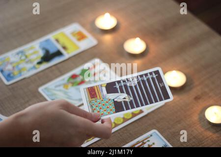 Istanbul,Turquie- Mars 06 2022: Fortune teller, montrant ou tenant des cartes de tarot alignées lisant sur une table en bois marron avec la main, bougies de thé brûlant. Banque D'Images