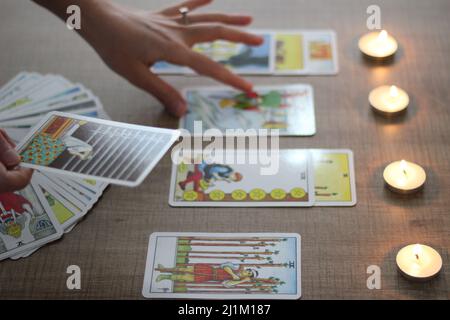 Istanbul,Turquie- Mars 06 2022: Fortune teller, montrant ou tenant des cartes de tarot alignées lisant sur une table en bois marron avec la main, bougies de thé brûlant. Banque D'Images