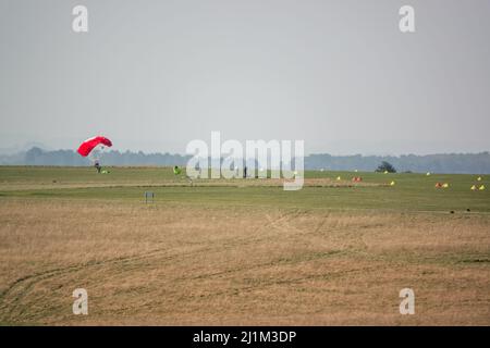 Saut en parachute arrivant sur un terrain d'aviation en herbe, ciel bleu Banque D'Images