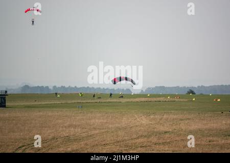 Saut en parachute arrivant sur un terrain d'aviation en herbe, ciel bleu Banque D'Images