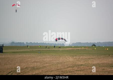 Saut en parachute arrivant sur un terrain d'aviation en herbe, ciel bleu Banque D'Images