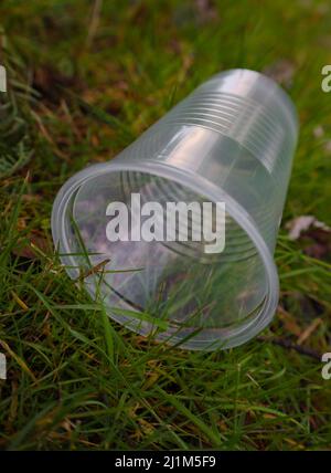 Herbe dans la cour avec une cuvette en plastique, propre, sur le sol. Déchets recyclables. Banque D'Images