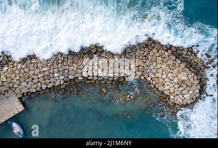 Drone aérien de vagues venteuses orageux heurtant avec force le brise-lames. Conditions météorologiques extrêmes en mer. Banque D'Images