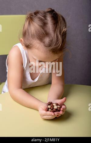 Une petite fille tient des boules de chocolat et de maïs blanc dans ses mains Banque D'Images