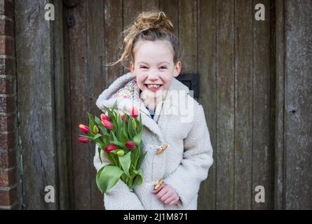 fille souriante tenant des fleurs tout en marchant dehors Banque D'Images