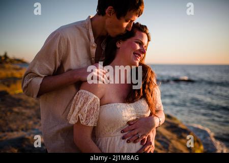 Mari Kissing femme enceinte sur la plage au coucher du soleil à San Diego Banque D'Images