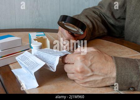 les mains des hommes tiennent des instructions pour le médicament et un grossissement g. Banque D'Images