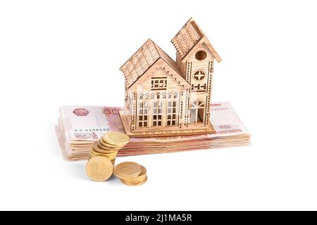 Une maison en bois et une pile de pièces en roubles russes sur fond blanc Banque D'Images