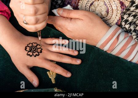 Dessin de henné menhdi tatouage sur les mains de fille dans un marché médiéval. Banque D'Images