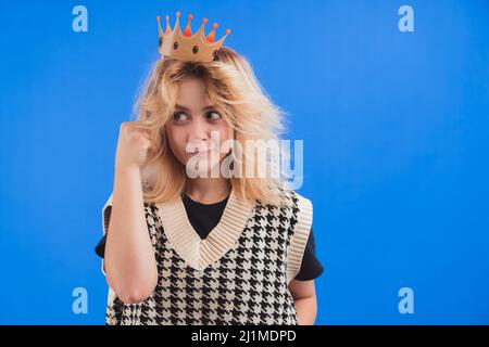 Portrait de studio sur fond bleu de drôle caucasien jeune fille millénaire tenant fausse couronne de partie, prêt pour la célébration. Photo de haute qualité Banque D'Images