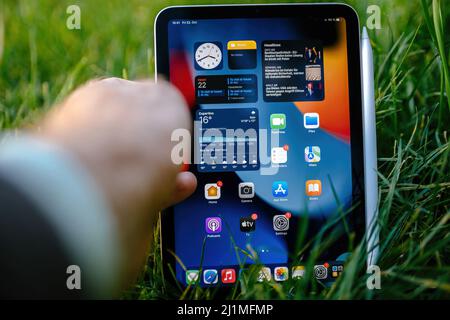 Paris, France - 21 octobre 2021 : main masculine atteignant la nouvelle tablette iPad pro Mini en pelouse verte Banque D'Images