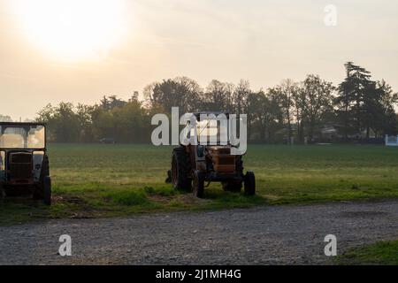 Vieux tracteurs d'époque dans les rayons du soleil tôt le matin sur la fromagerie dans le nord de l'Italie Banque D'Images