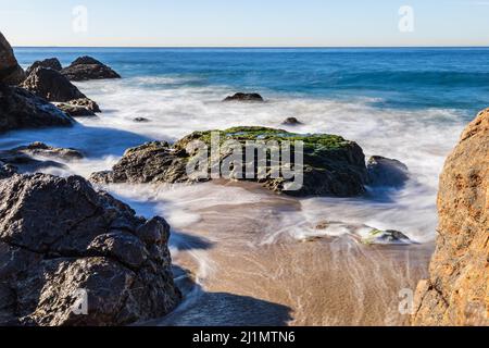 Rocky Beach à Malibu, Californie. Les vagues s'éloignent du rivage sablonneux; bleu océan Pacifique en arrière-plan. Banque D'Images