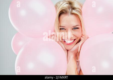 Je ne sais pas pourquoi, mais je suis si heureux. Photo courte d'une belle jeune femme posant avec des ballons roses. Banque D'Images