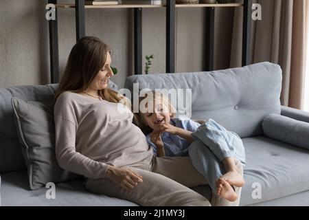 Jeune femme enceinte souriante jouant avec un petit fils. Banque D'Images