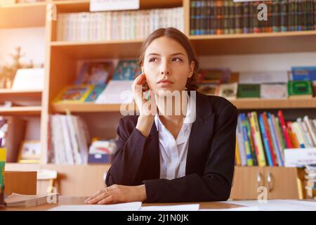 Jeune femme d'affaires pensive planifiant l'horaire de travail écrire dans le carnet, assis à la table de travail, femme directrice administrative, faire des notes information, dictée de comptabilité et d'analyse Banque D'Images