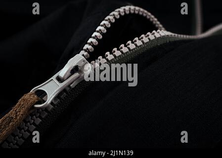Fermeture éclair grise sur les vêtements noirs. Fermoir de la veste Banque D'Images