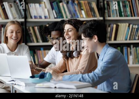 Les étudiants multiethniques utilisent un ordinateur portable pour étudier ou s'amuser dans la bibliothèque Banque D'Images