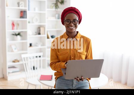 Femme noire millénaire souriante entrepreneur travaillant à la maison Banque D'Images