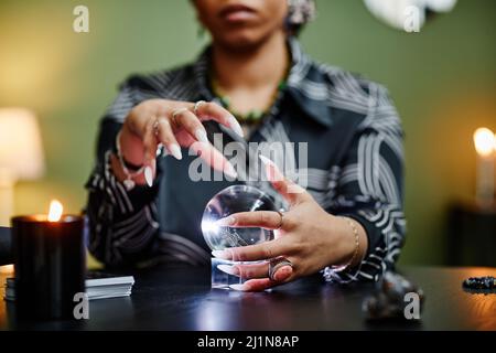 Gros plan de la chance de teller regardant dans la boule de cristal à la seance spirituelle, se concentrer sur les mains de femmes gesturant Banque D'Images
