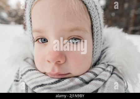 petite fille dans des vêtements chauds dans une forêt d'hiver Banque D'Images